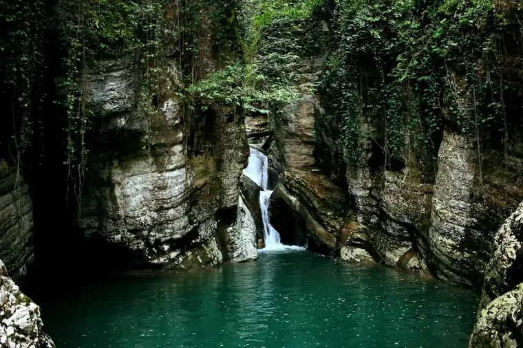 Looking out from a cave onto a sunlit green canyon
