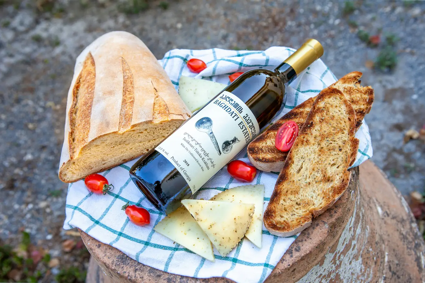 Bottle of Georgian wine with bread, cheese and tomatoes on a blue checkered cloth